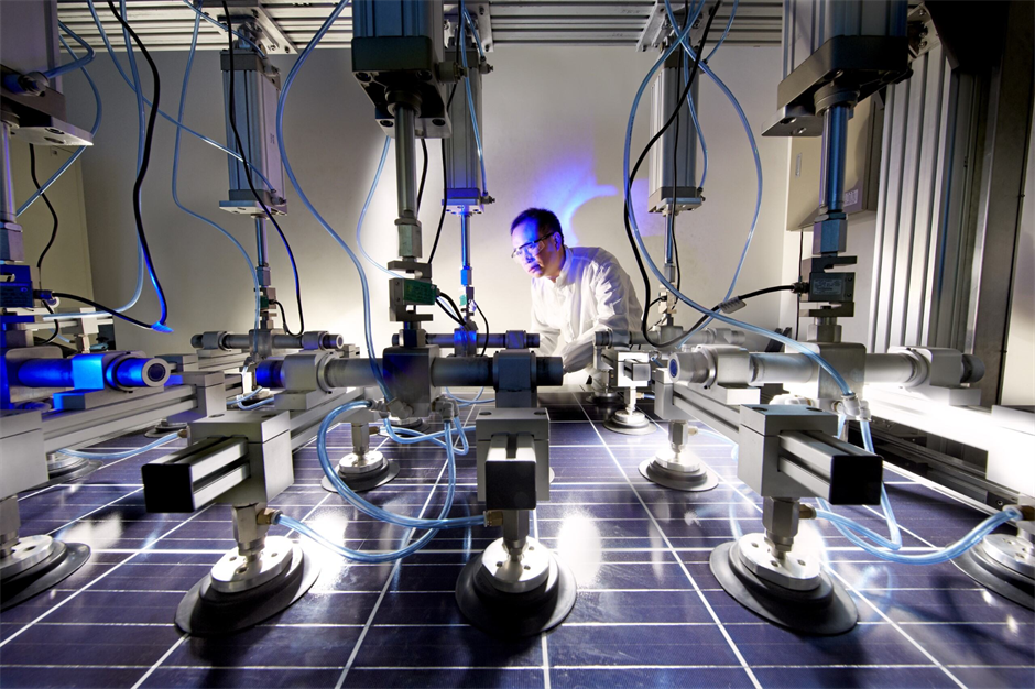 A scientist inspects solar panels under specialized testing equipment in a laboratory.